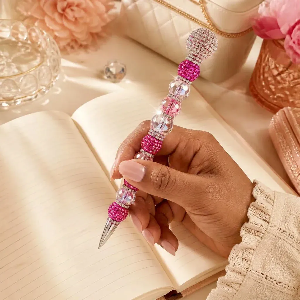 A hand holding a sparkling beaded pen